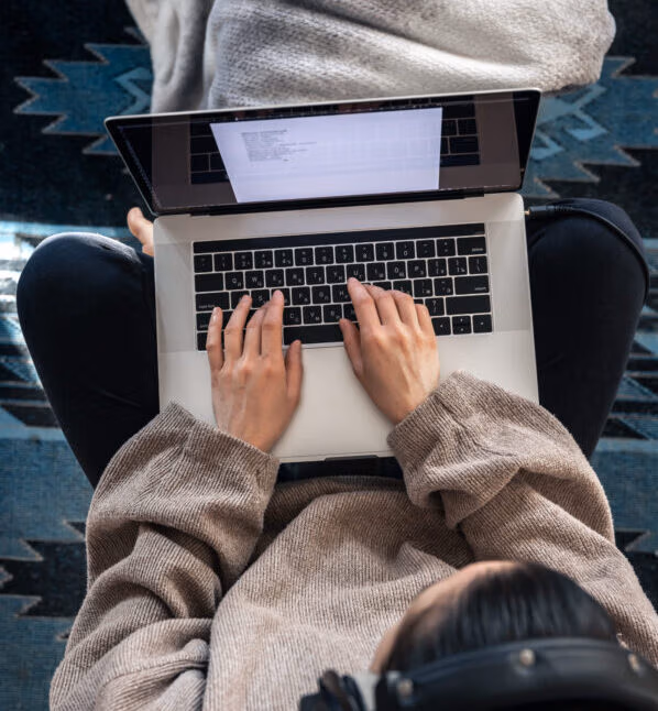 A woman working sitting at a laptop, top view.